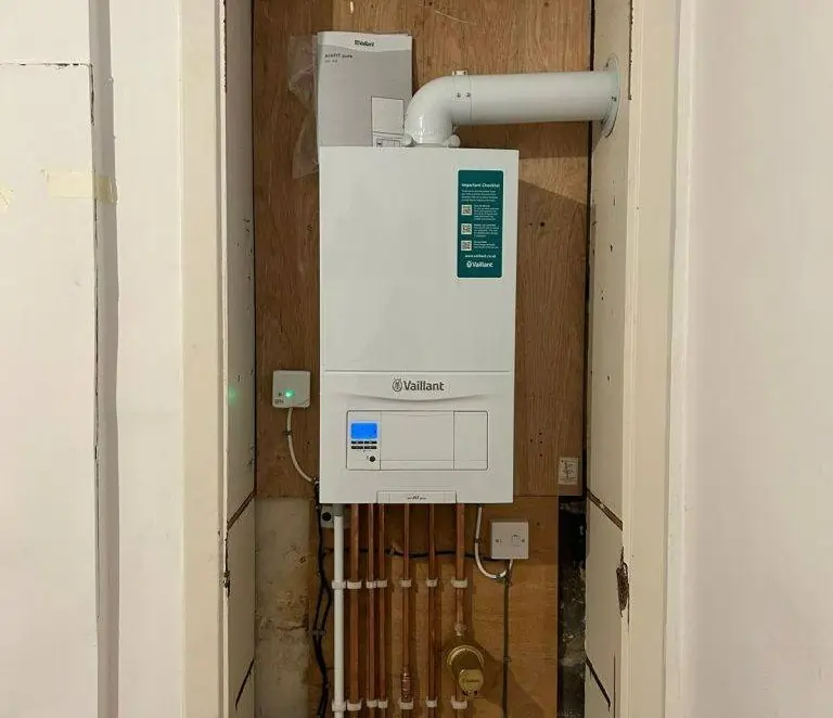 Newly installed energy-efficient Vaillant boiler with connected pipework inside a utility cupboard, demonstrating modern heating system efficiency.